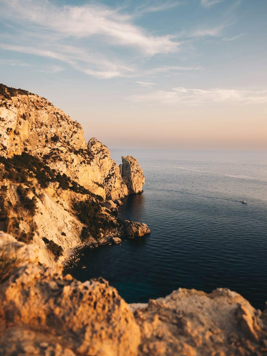 Falésias douradas descendo para o mar em Ibiza, na luz do fim de tarde.