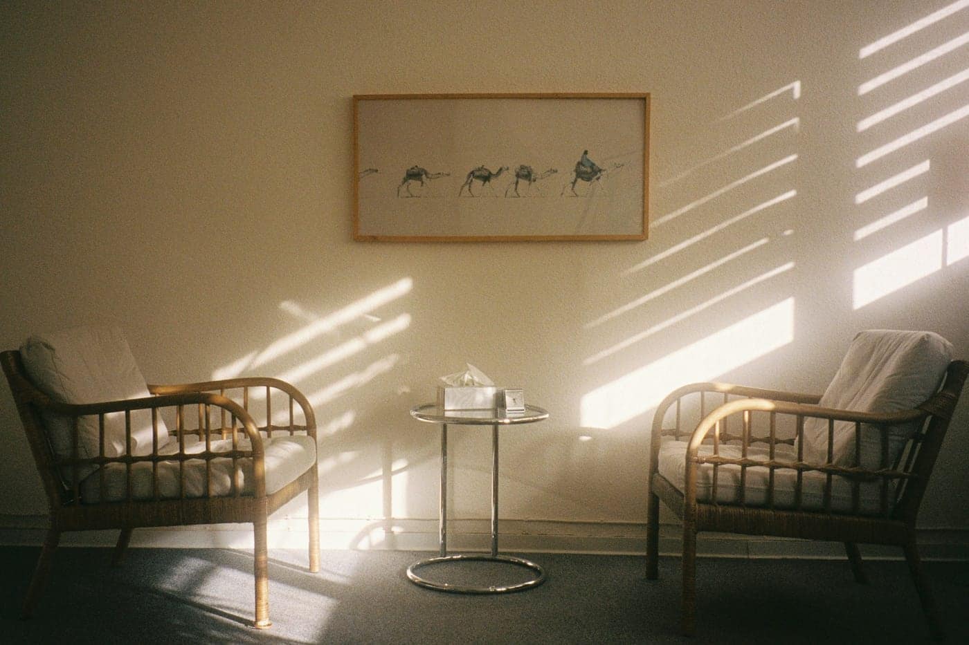 Duas poltronas de vime frente a frente, com a luz da tarde entrando pelas persianas.